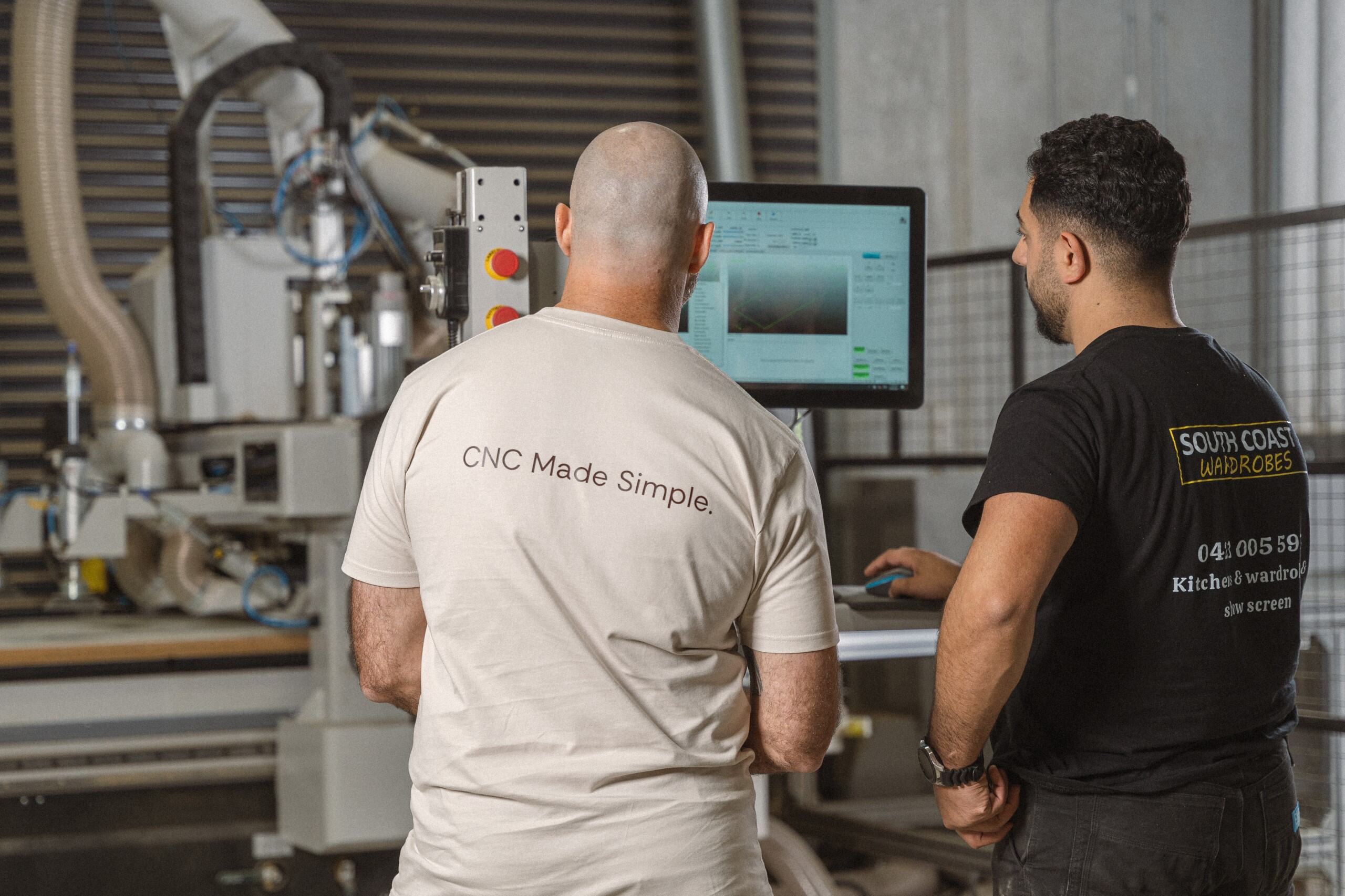Two men are concentrated on the monitor in a workshop